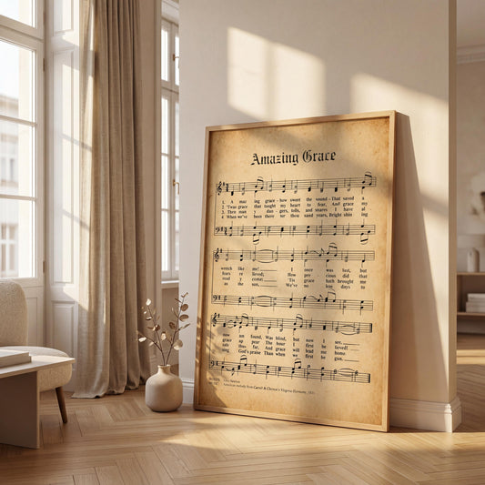 a large framed sheet of music titled "Amazing Grace" with musical notation and lyrics, placed on a wooden floor in a room with a window and a vase of flowers.