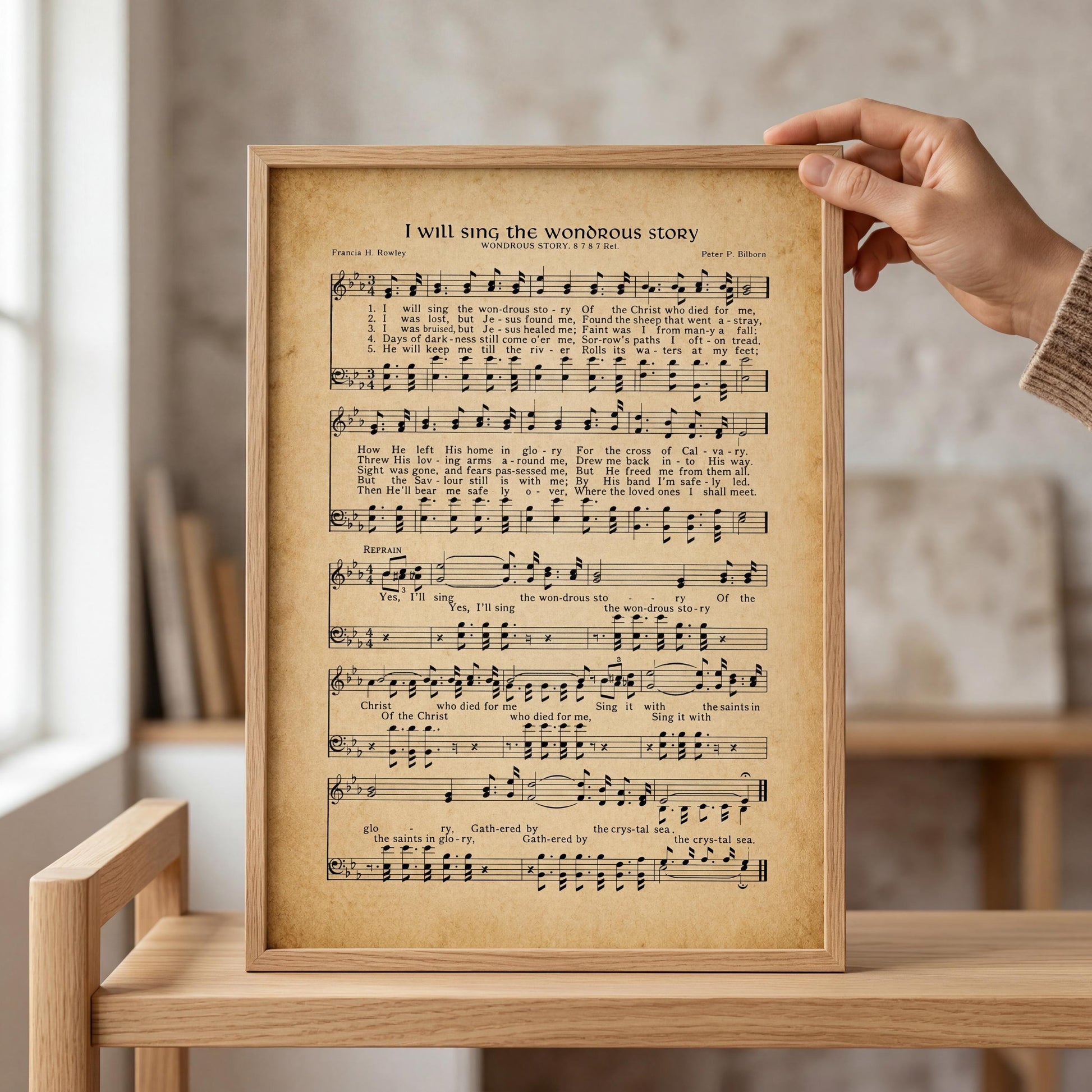 A framed sheet of music titled "I will sing the wonderful story" is being held up in front of a person's hand.