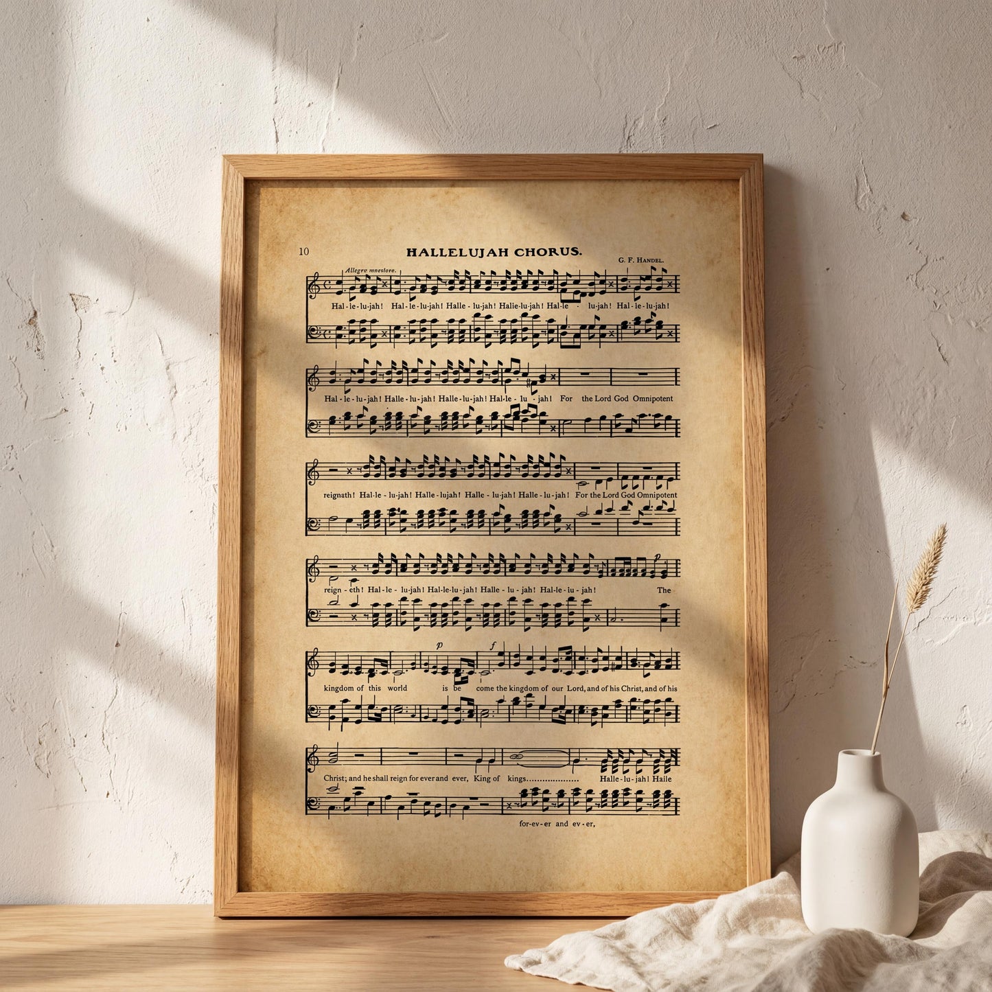 a framed sheet music print of a hymn titled "Balleluah Chorus" displayed on a wall, with a white vase and a plant in the foreground.