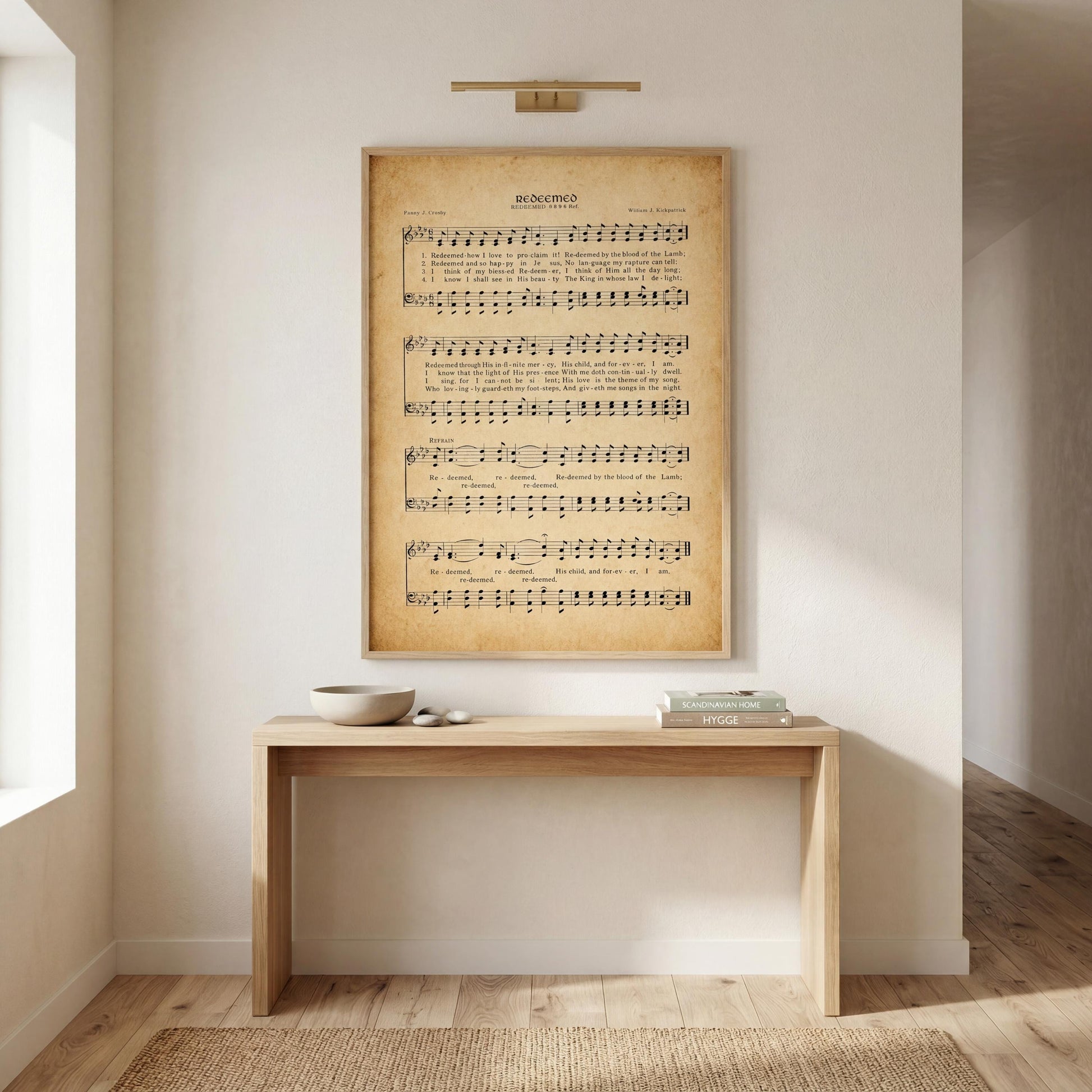a wooden console table with a bowl and a book on top, set against a white wall with a framed sheet music poster hanging above it.