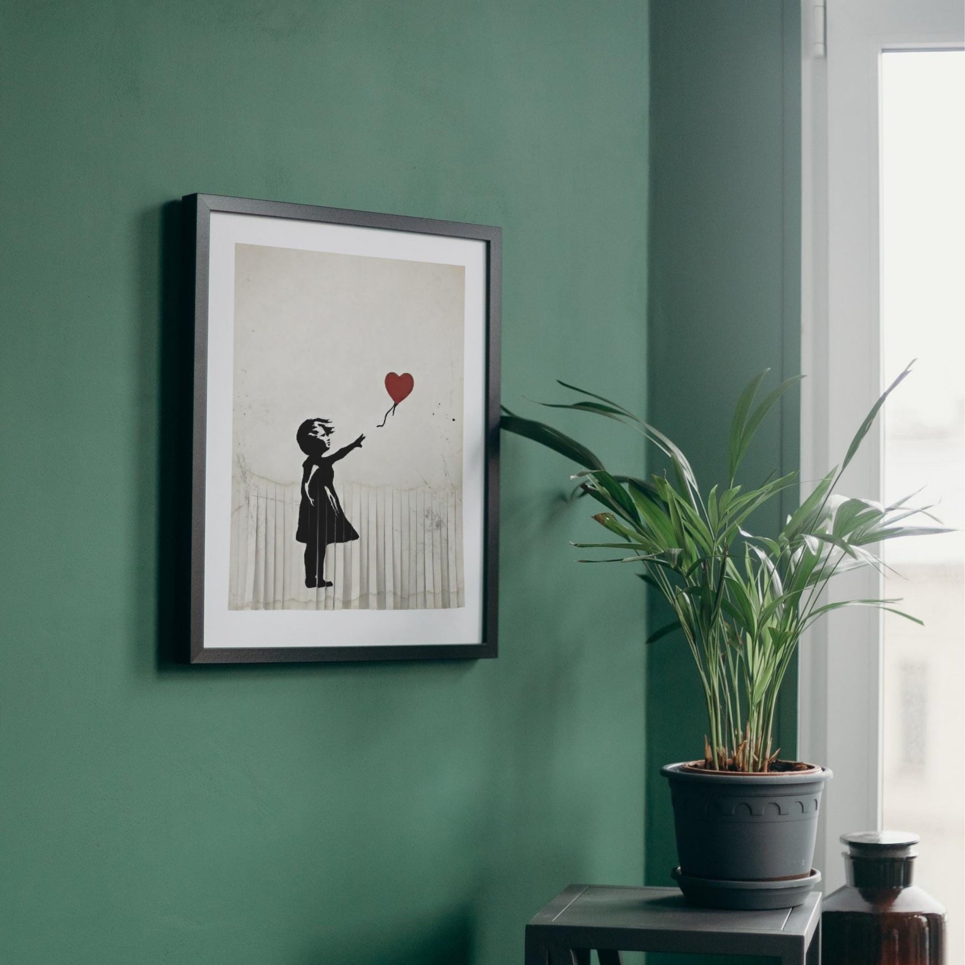 a framed artwork of a person holding a heart-shaped balloon, hanging on a green wall next to a potted plant.