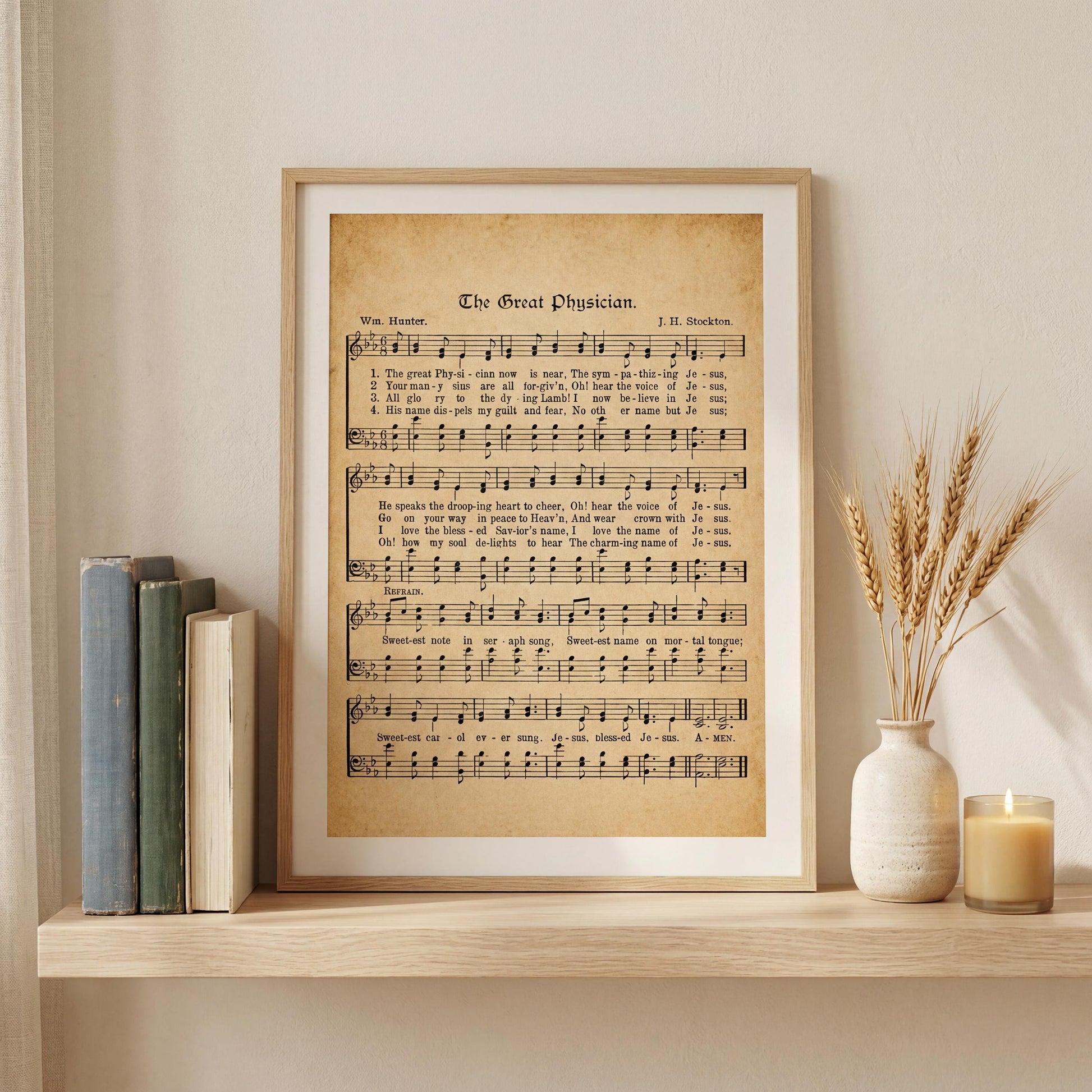 a framed sheet music poster of "The Great Physician" with a candle and books on a shelf.