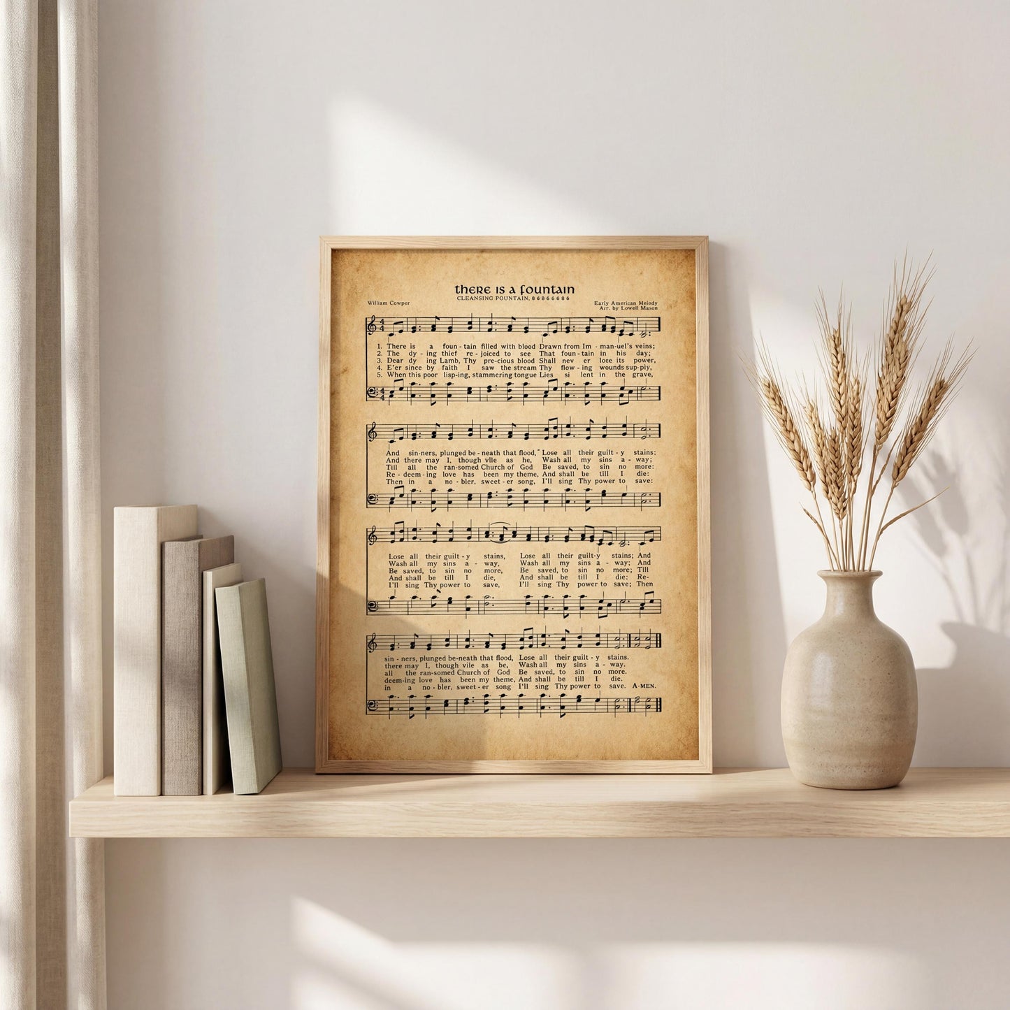 a framed sheet music print of a hymn titled "There is a fountain" displayed on a shelf next to a vase with wheat stalks.