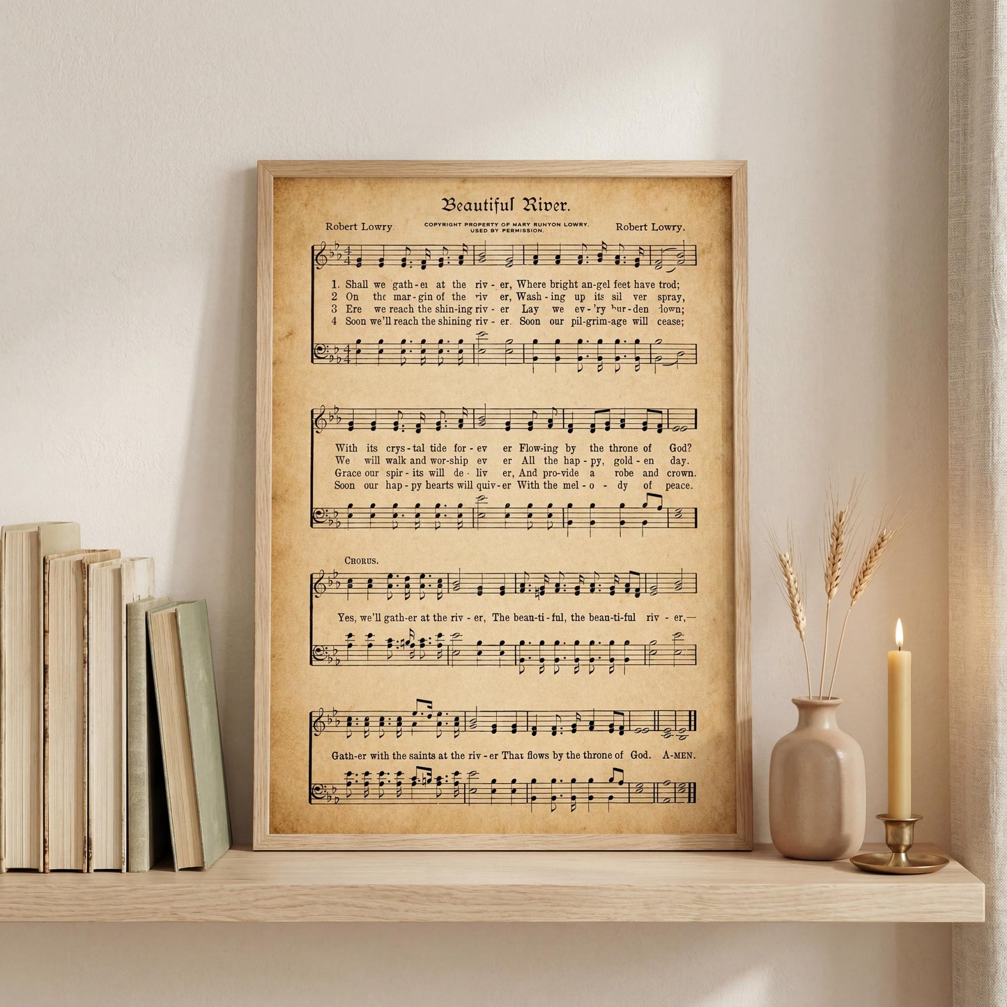 a framed sheet music poster of a hymn titled "Beautiful River" by Robert Loryy, displayed on a shelf next to a vase with wheat stalks and a lit candle.