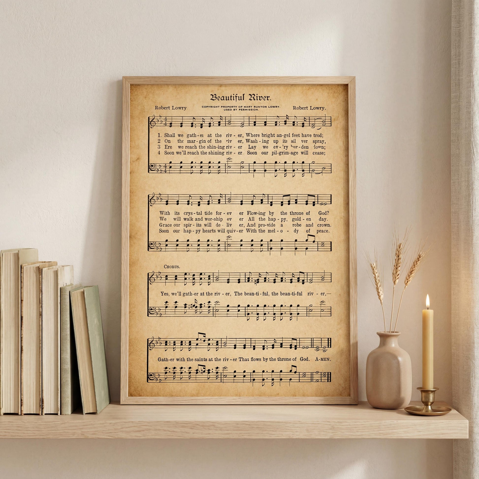 a framed sheet music poster of a hymn titled "Beautiful River" by Robert Loryy, displayed on a shelf next to a vase with wheat stalks and a lit candle.