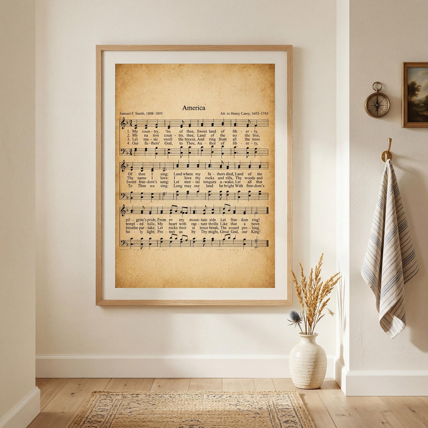 a framed sheet music print of a hymn titled "America" hanging on a wall in a room with a vase of dried flowers and a clock on the wall.