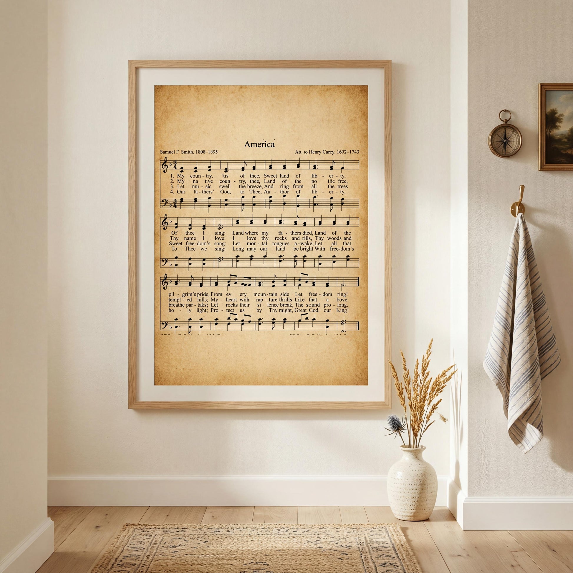 a framed sheet music print of a hymn titled "America" hanging on a wall in a room with a vase of dried flowers and a clock on the wall.