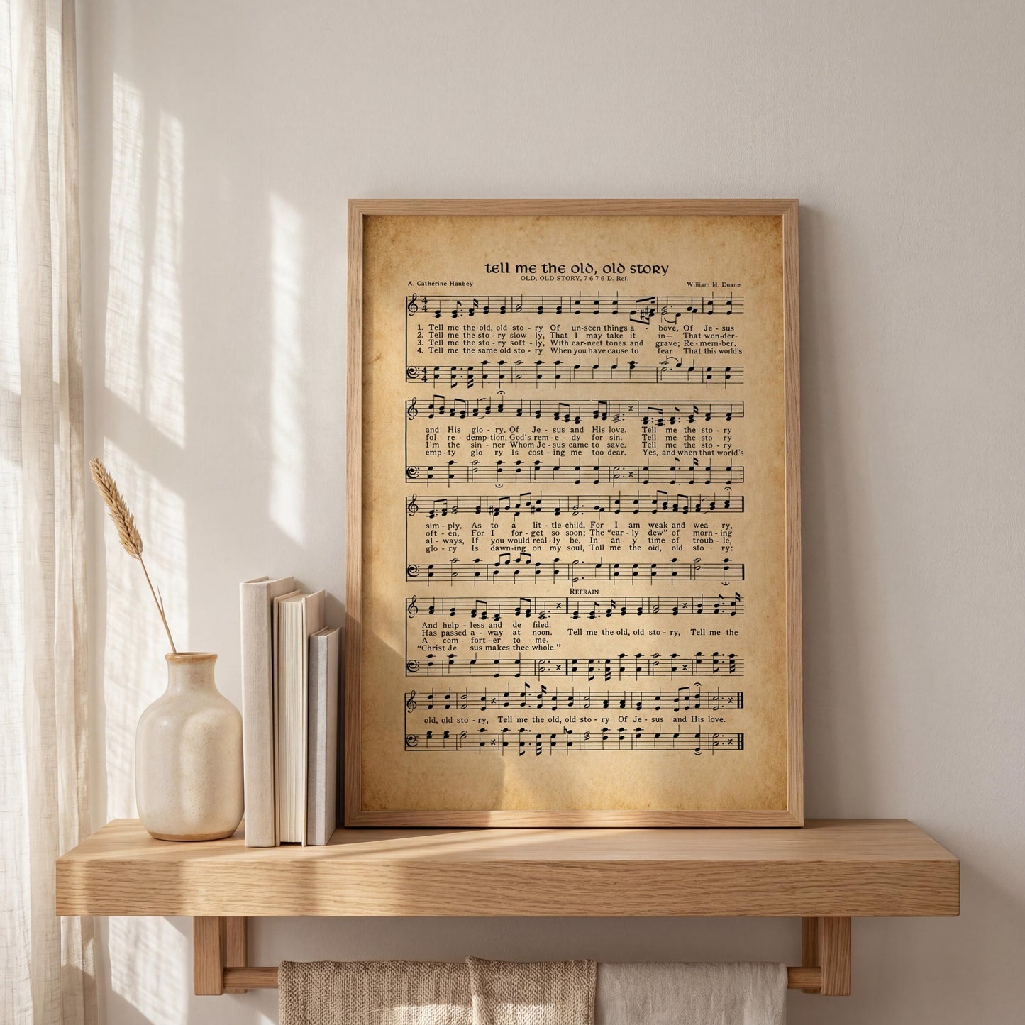 a framed sheet music print of a hymn or song lyrics, placed on a wooden shelf next to a vase with a sprig of wheat.