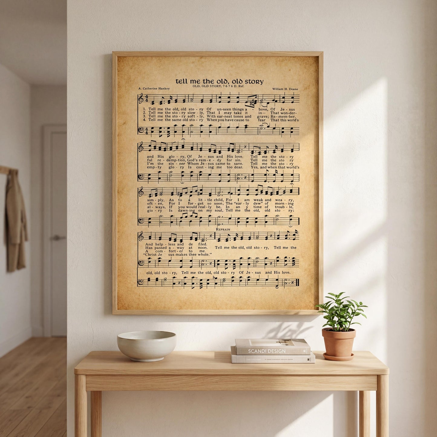 a wooden table with a white bowl and a small potted plant on it. Above the table, there is a framed sheet of music with lyrics and musical notation.