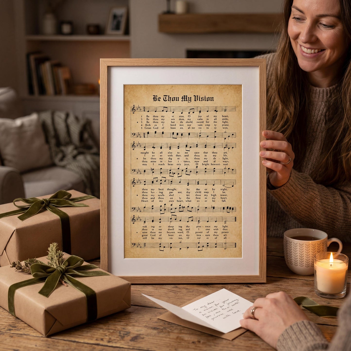 A woman is holding up a framed sheet of music with lyrics, surrounded by wrapped gifts and a candle on a table.