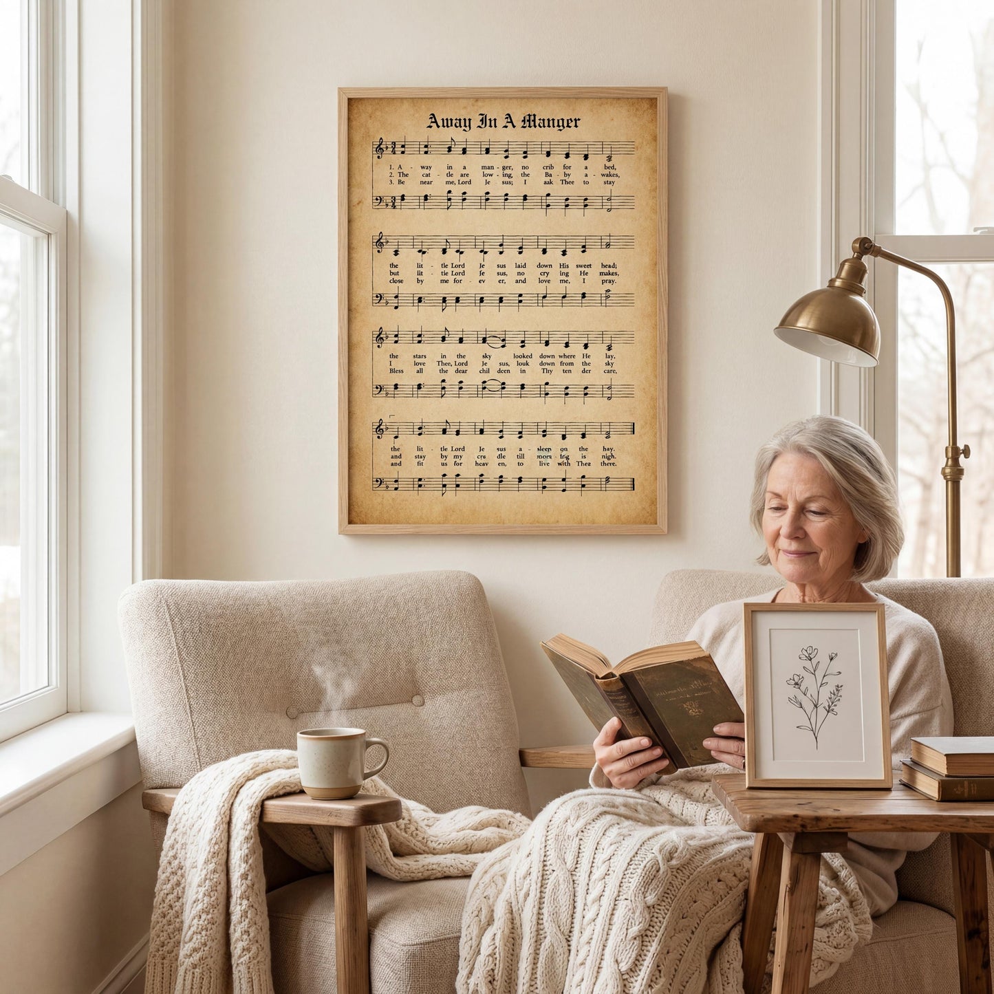 An elderly woman is sitting in a chair, reading a book, with a framed sheet music poster of a hymn hanging on the wall behind her.