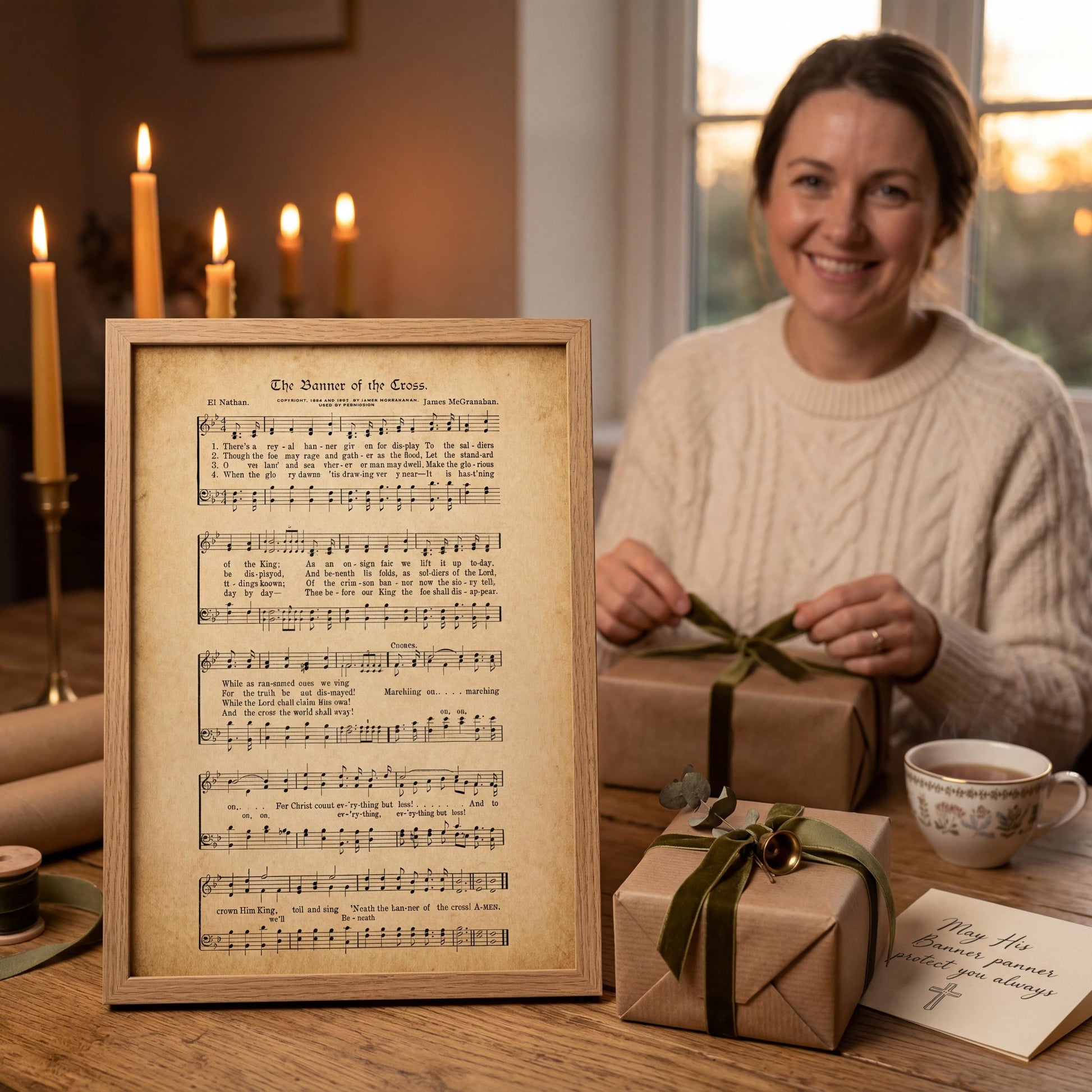 A woman is sitting at a table with a framed sheet of music, wrapped gifts, and a cup of tea.
