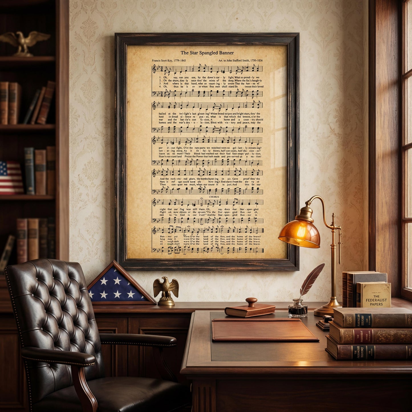 a framed sheet music poster of "The Star Spangled Banner" hanging on a wall above a desk with a lamp, books, and an American flag.