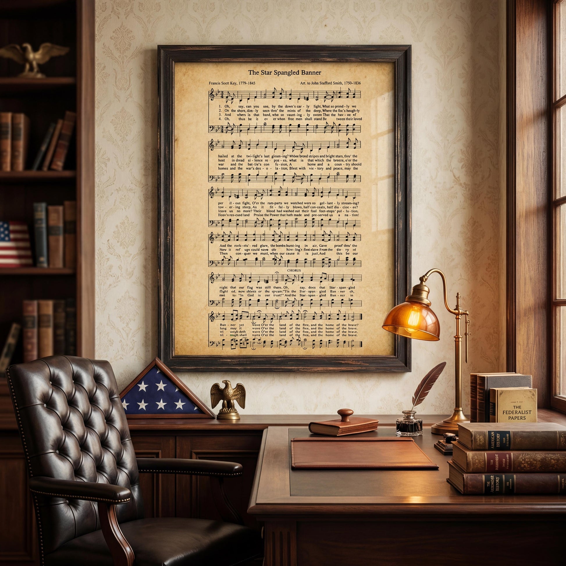 a framed sheet music poster of "The Star Spangled Banner" hanging on a wall above a desk with a lamp, books, and an American flag.