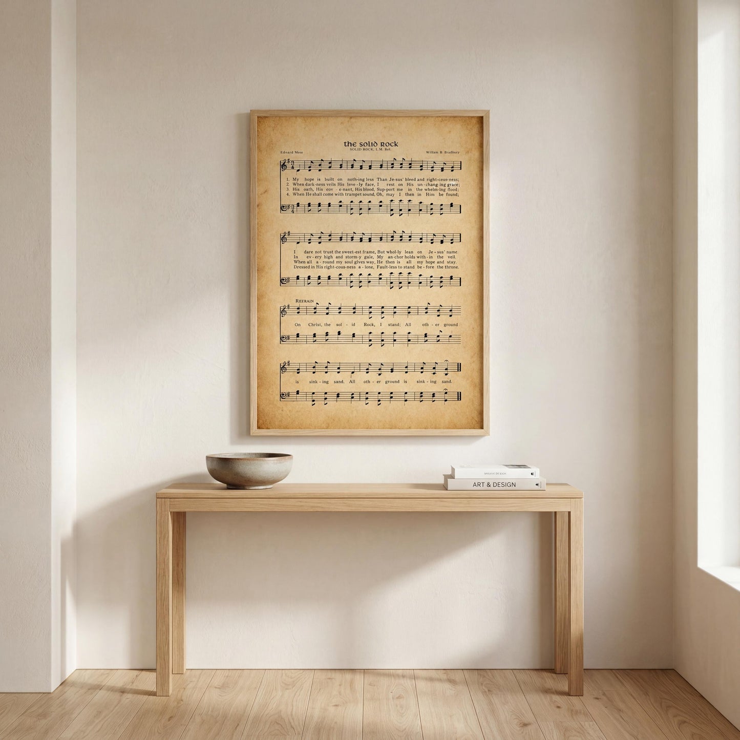 a wooden table with a bowl on it, and a framed sheet of music is hanging on the wall above the table.
