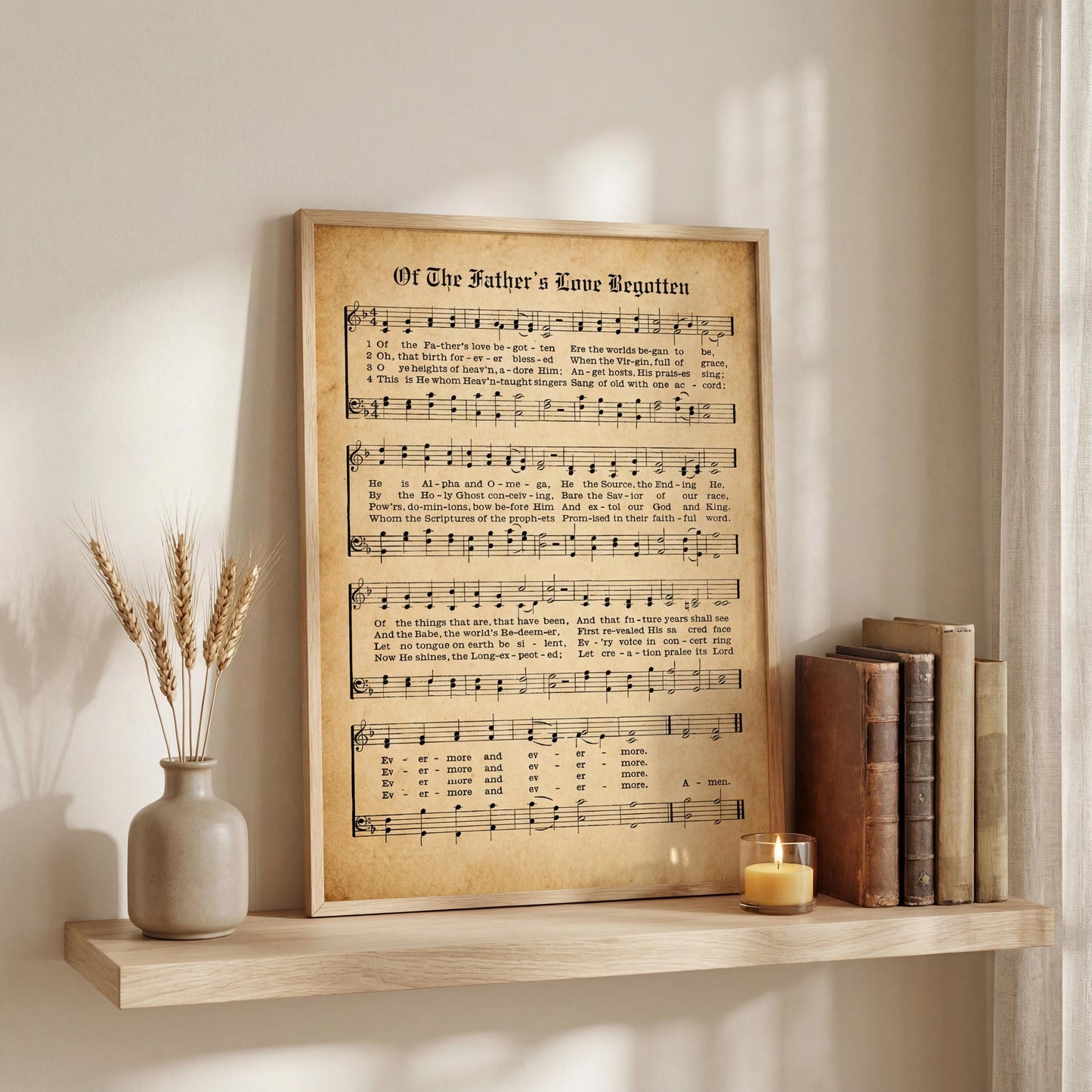 a framed sheet music poster titled "Of The Father's Love Begotten" displayed on a wooden shelf, accompanied by a vase of wheat stalks and a lit candle.