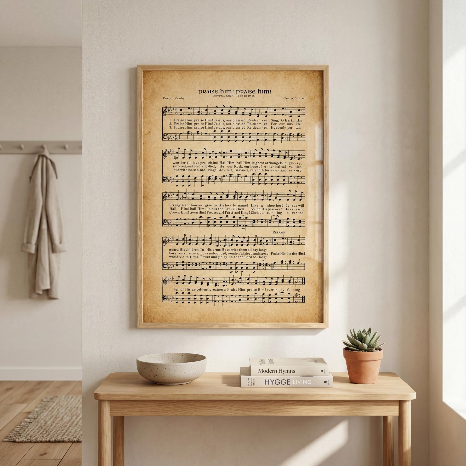a framed sheet music poster of a hymn, a wooden table with a bowl and a potted plant, and a bookshelf with books.